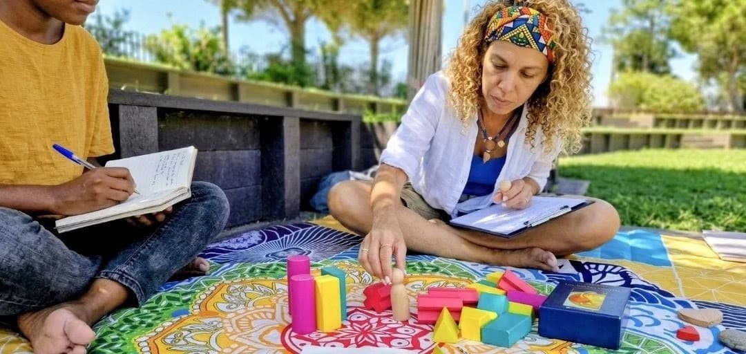 Djamila accompagne une participante avec les figurines en bois et les cartes pendant une constellation systémique