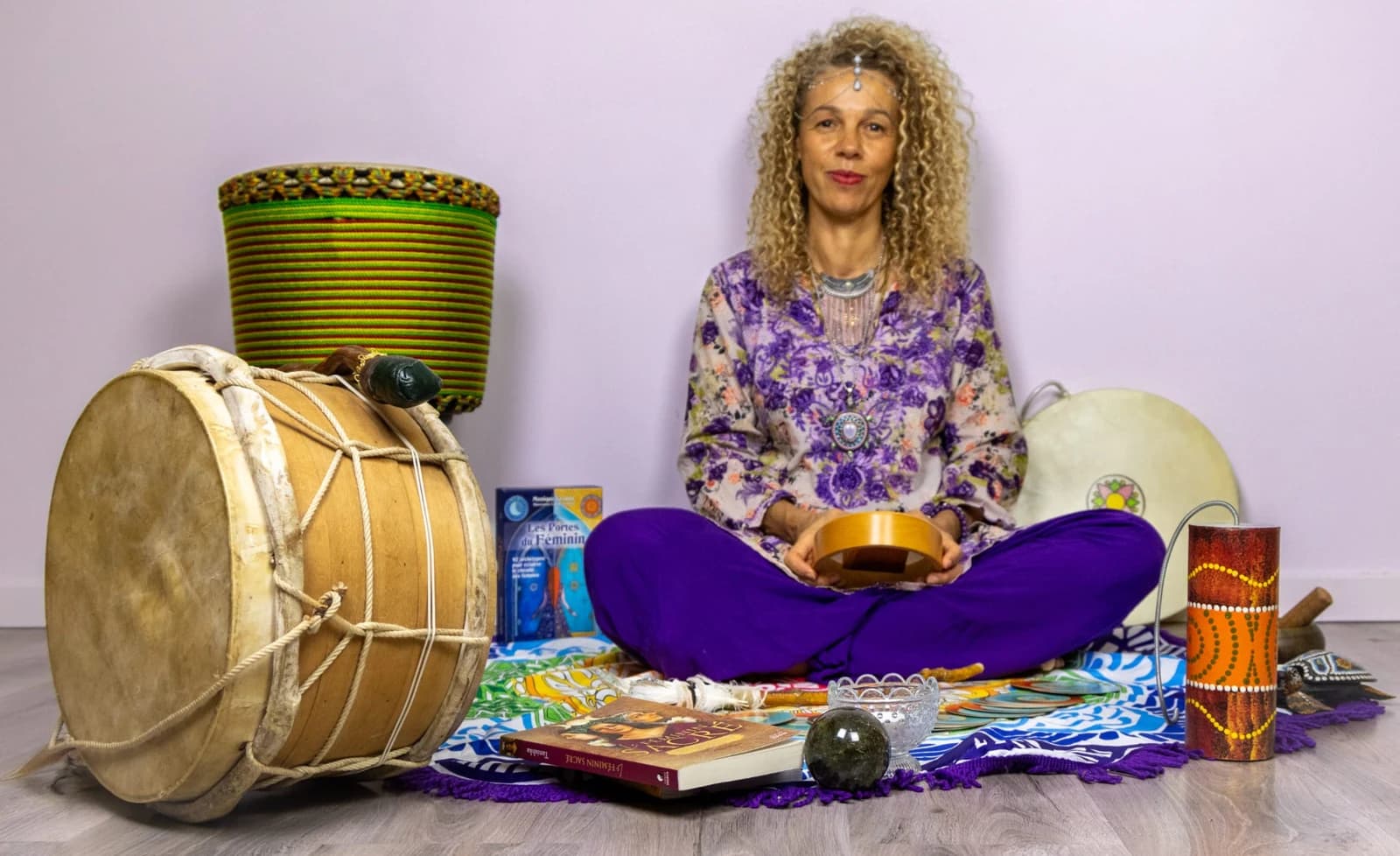 Djamila assise sur son tapis de constellation, entourée de tambours, percussions et supports